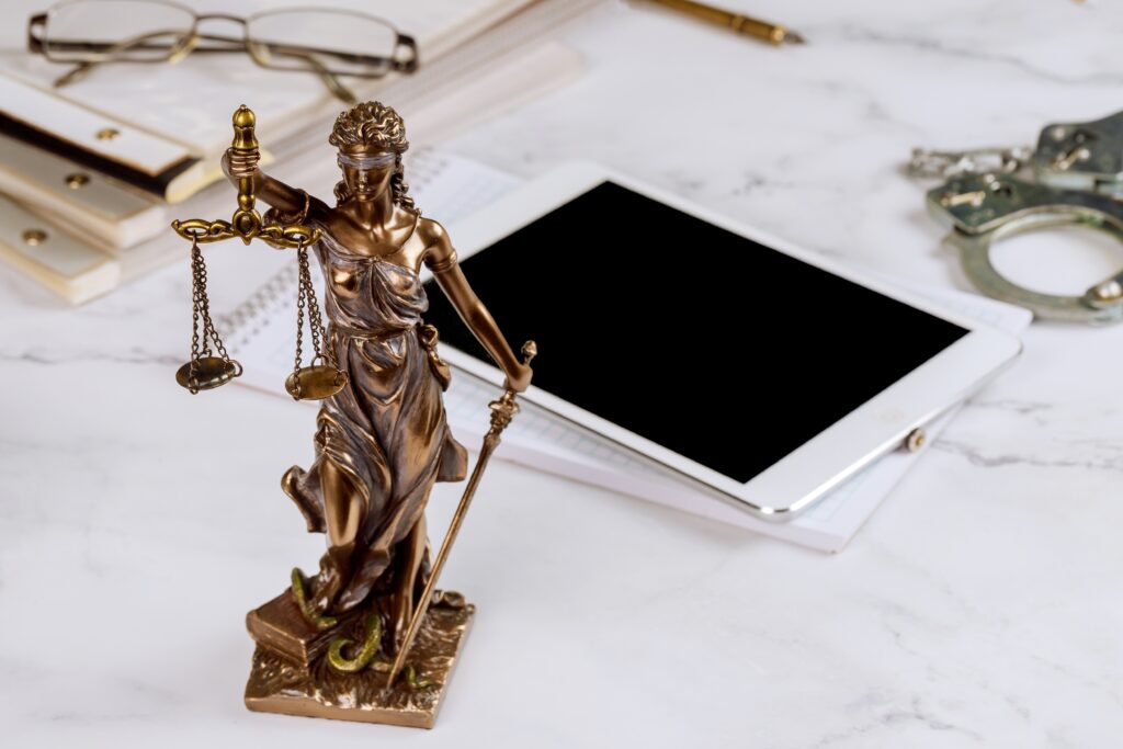 lawyer office statue of justice with scales and lawyer working on a digital tablet
